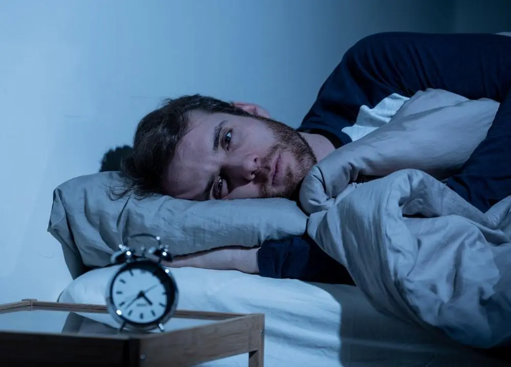 Man lying awake in bed at night, unable to sleep