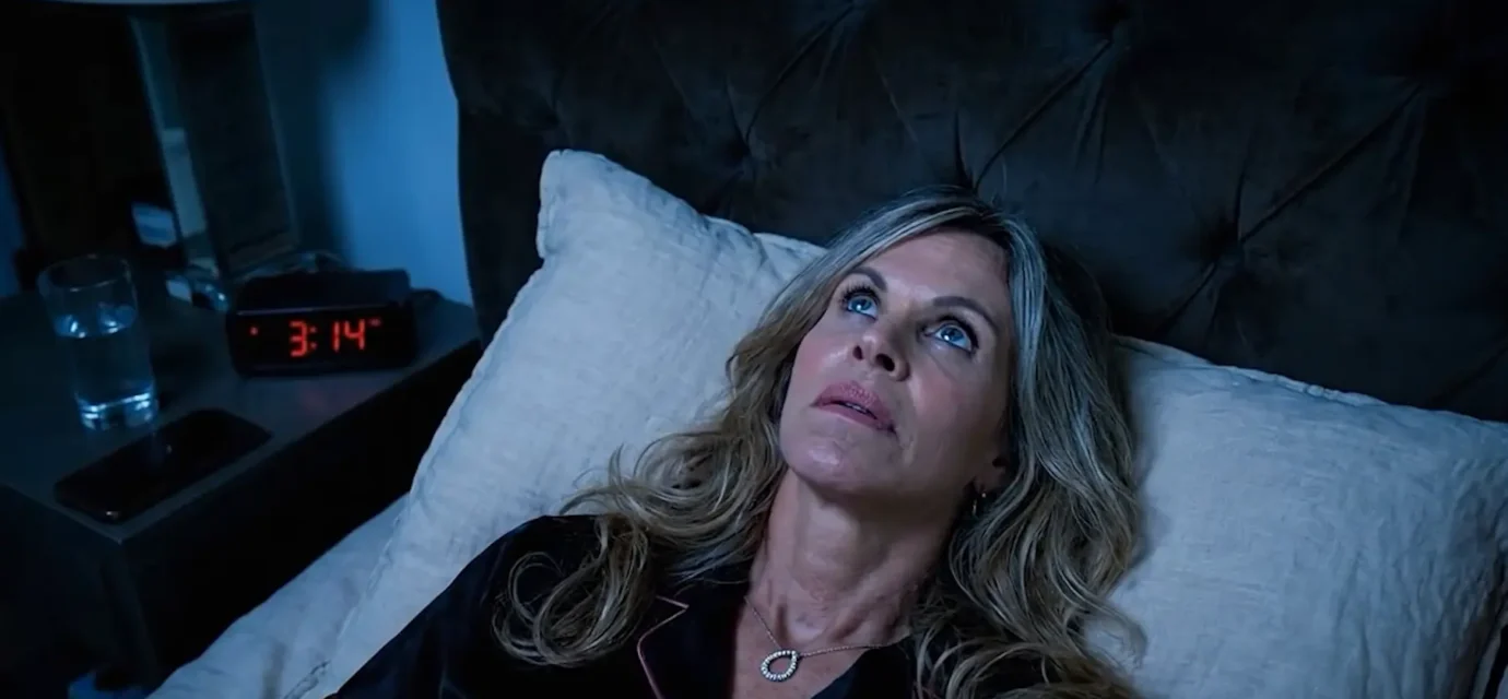 person lying awake in bed at night unable to sleep , looking at the clock 3am